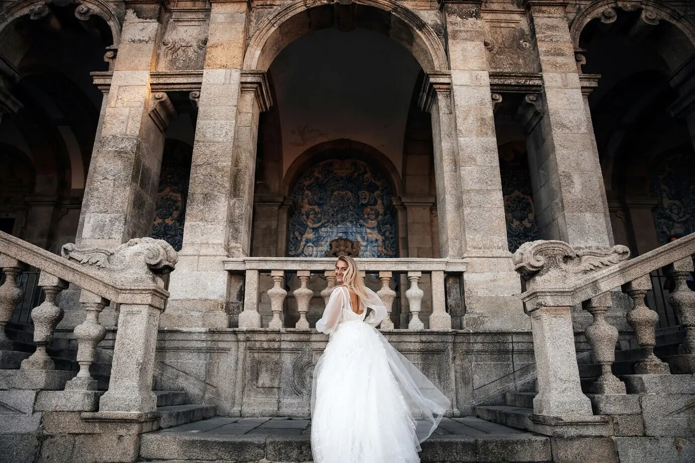 Eine Braut steht halb gedreht auf der Treppe des antiken Gebäudes.